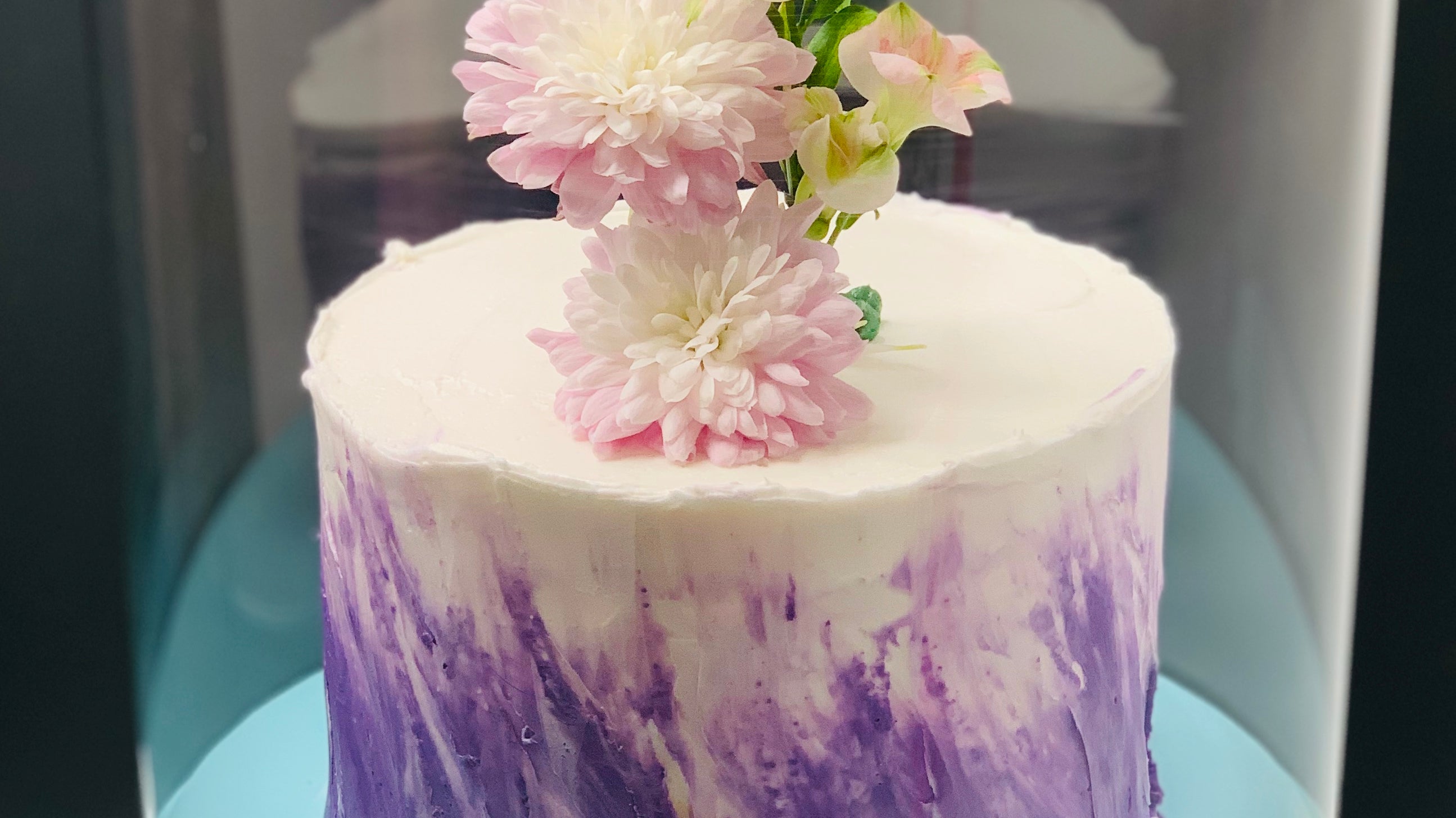 White and purple round cake in round clear box