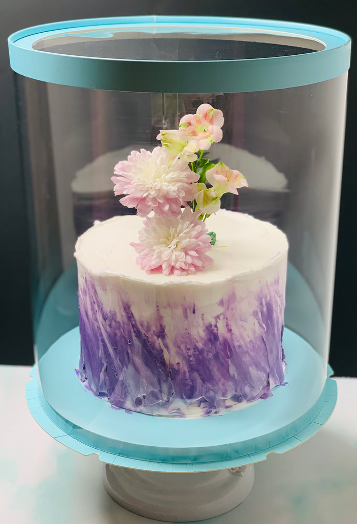 White and purple round cake in round clear box