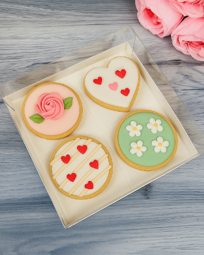 Decorative cookies in a box with pink flowers on a wooden surface