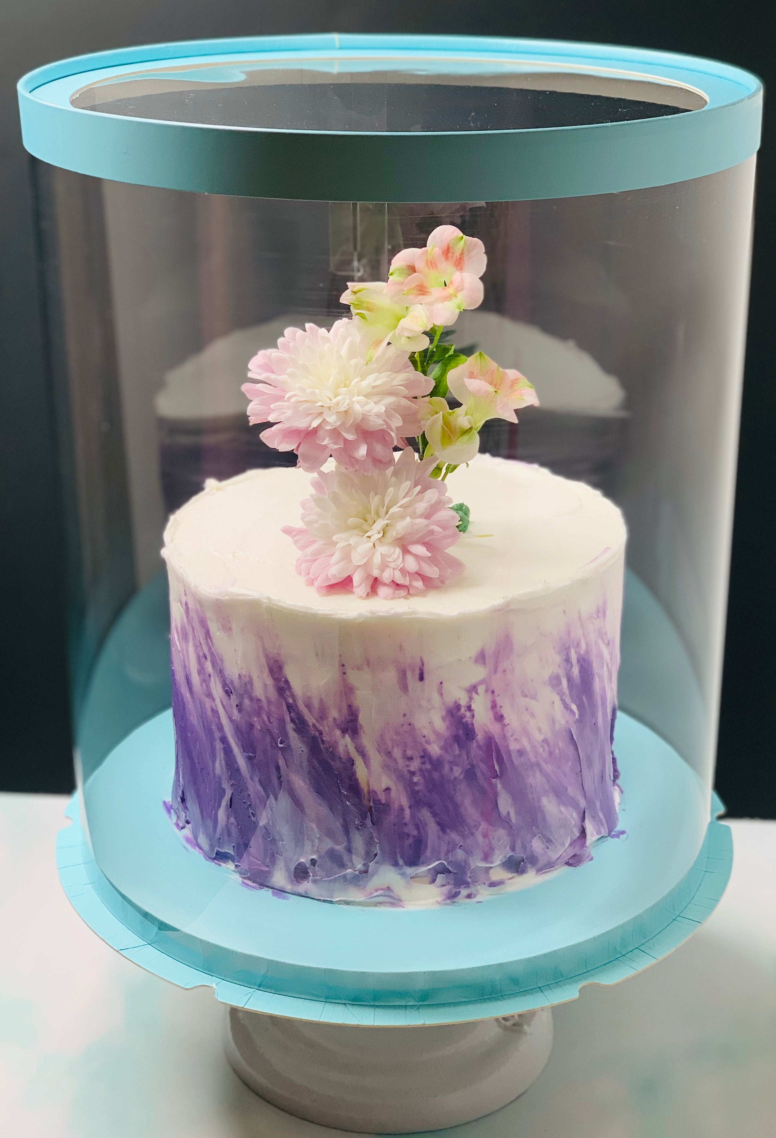 White and purple round cake in round clear box