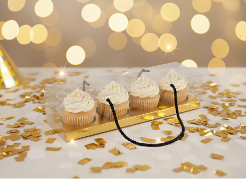 Decorative necklace on a tray with cupcakes and gold confetti against a bokeh light background