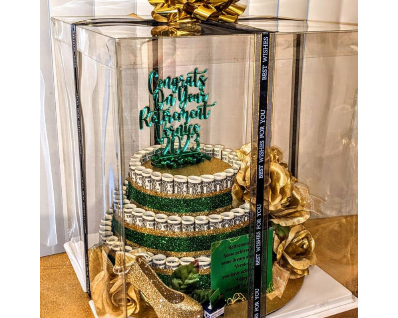 Decorative cake with green and gold elements in a clear box