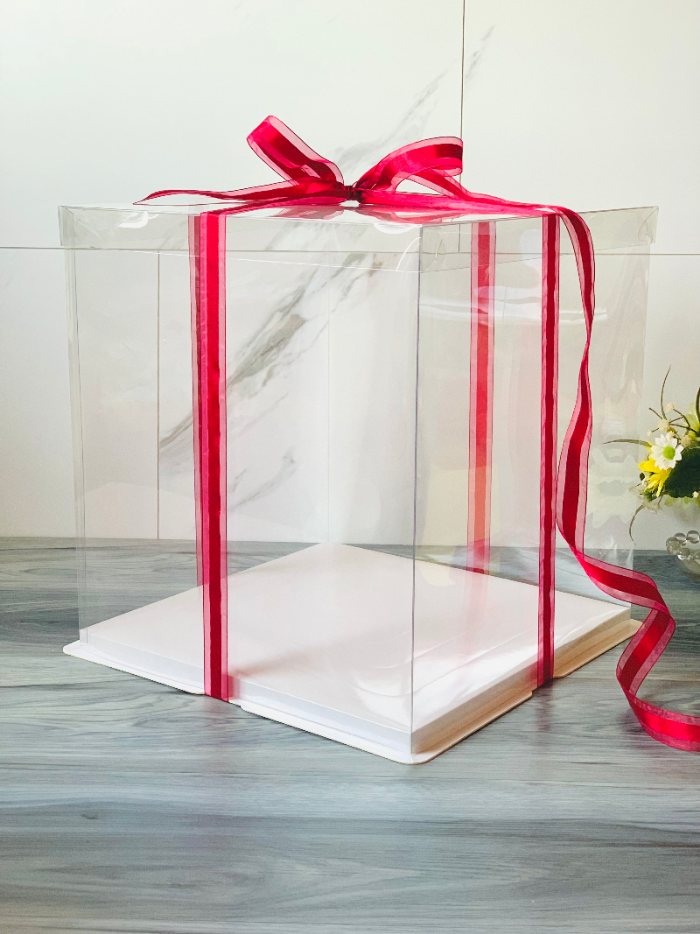 Clear gift box with a red ribbon on a marble surface