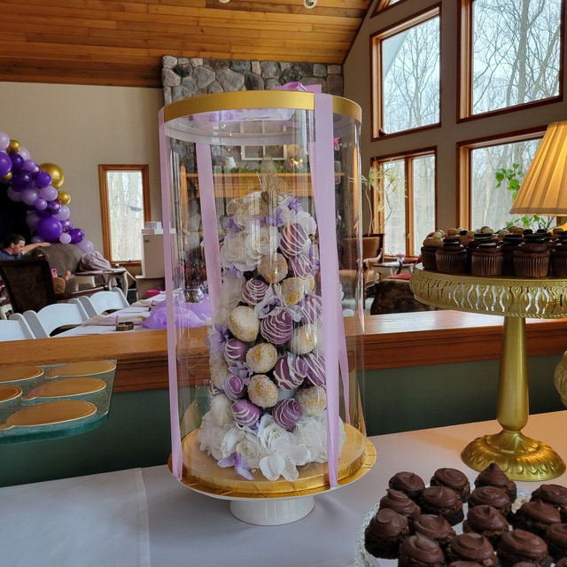 Decorative cake with flowers in a glass dome on a table with chocolate strawberries