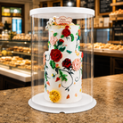 Decorative cake with floral designs in a clear display case on a bakery counter.
