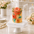 Decorative cake with floral decorations on a white stand, surrounded by flowers and plates.
